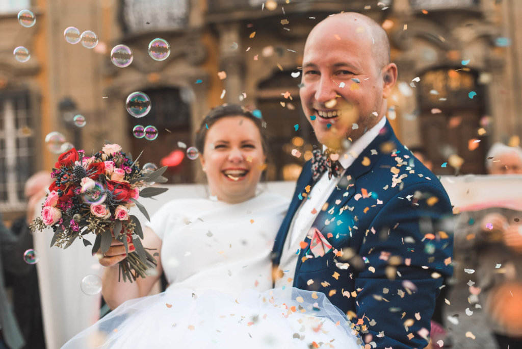 Brautpaar im Konfettiregen bei Standesamt Trauung in Schwäbisch Hall mit Seifenblasen und lachenden Gesichtern bei Winterhochzeit