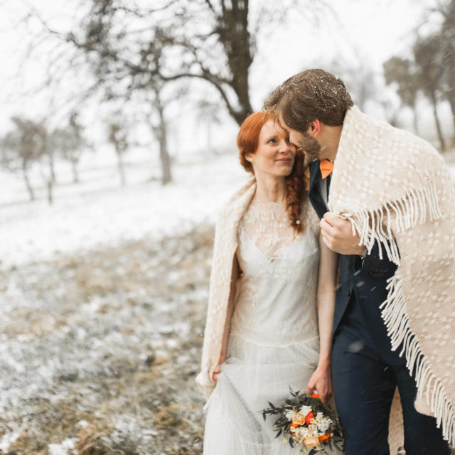 Brautpaar feiert Winterhochzeit mit Schnee auf dem Landgut Halsberg mit Winterdecke
