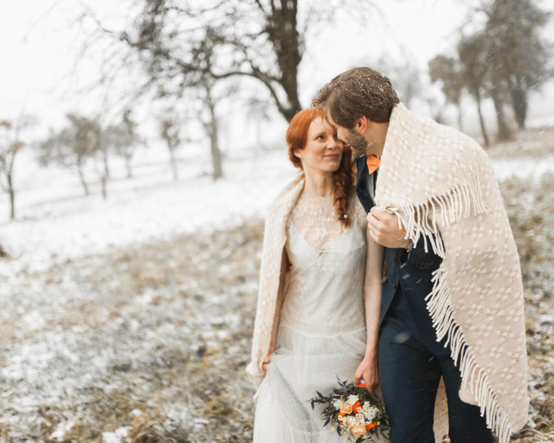 Brautpaar feiert Winterhochzeit mit Schnee auf dem Landgut Halsberg mit Winterdecke