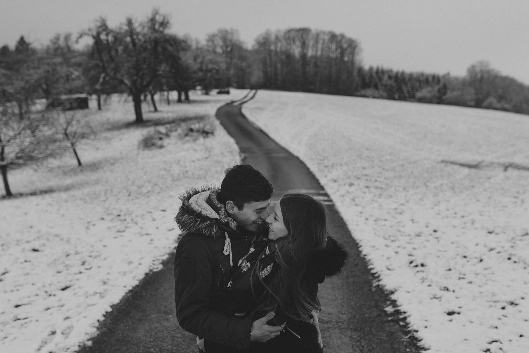 Lachendes Paar während Shooting auf Straße und Feldweg im Schnee
