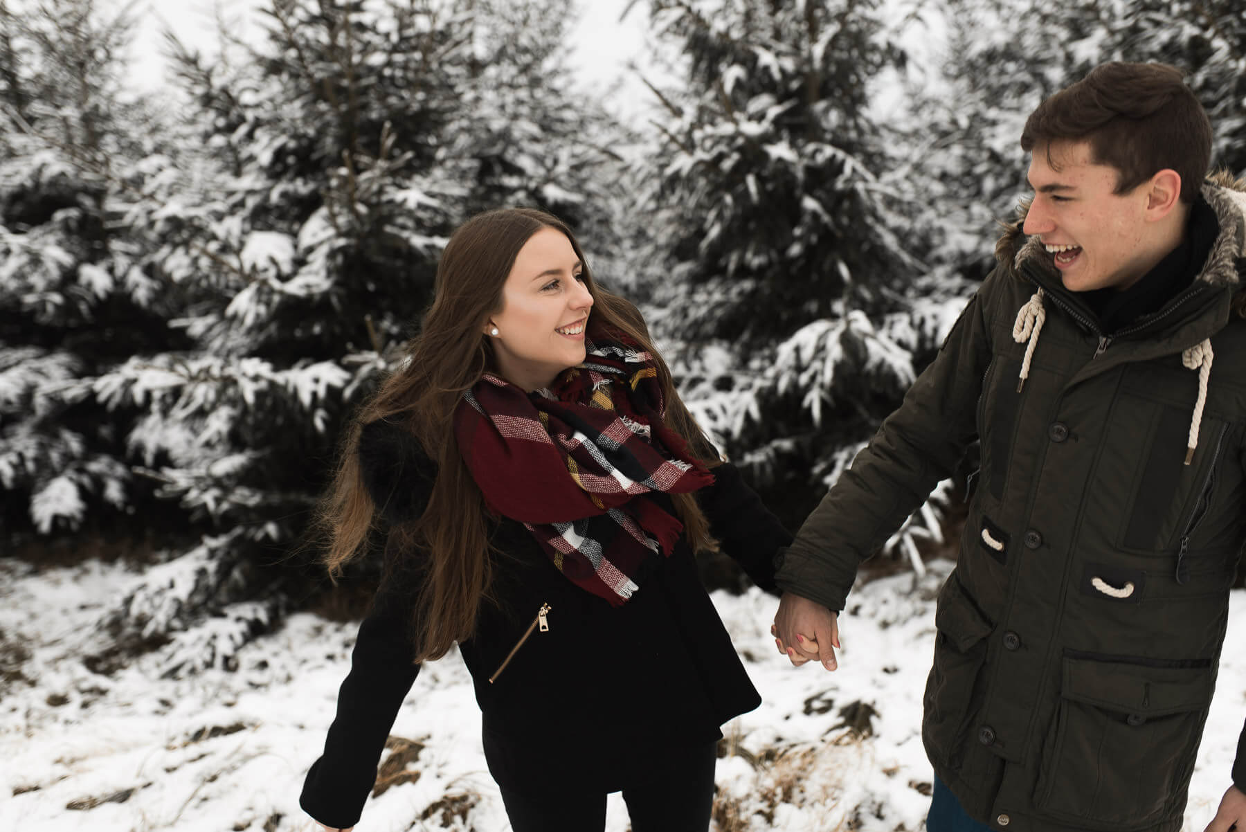 Lachendes Paar im Winter im Wald nach Schneefall 