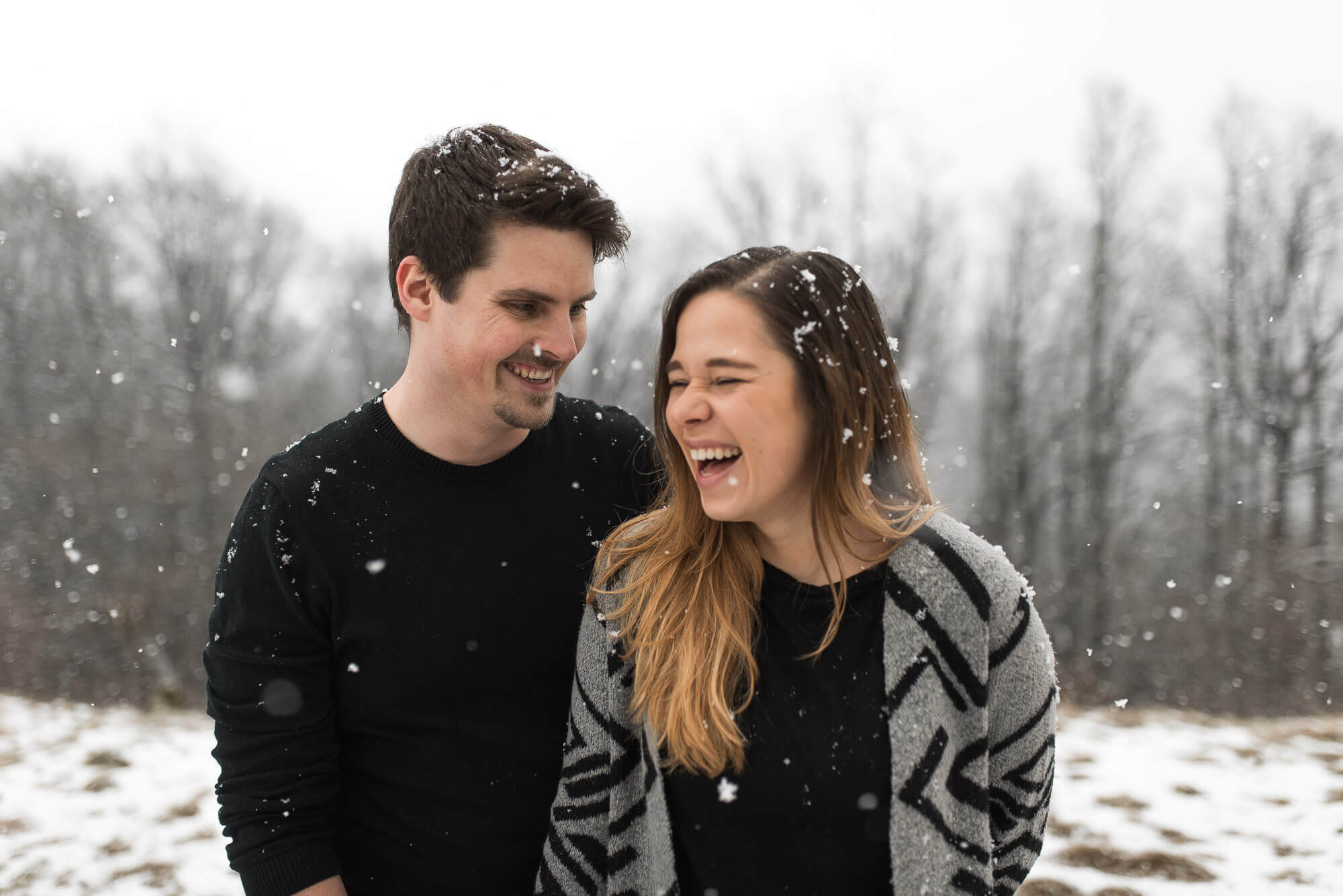 Lachendes Paar beim Engagementshoot im Winter bei Schneefall auf dem Einkorn bei Schwäbisch Hall