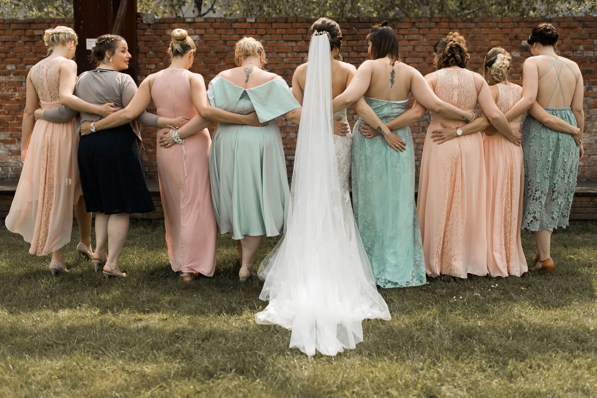Braut steht mit Bridemaids mit dem Rücken zur Kamera in der Natur auf Hochzeit im Werkcafe Ludwigsburg