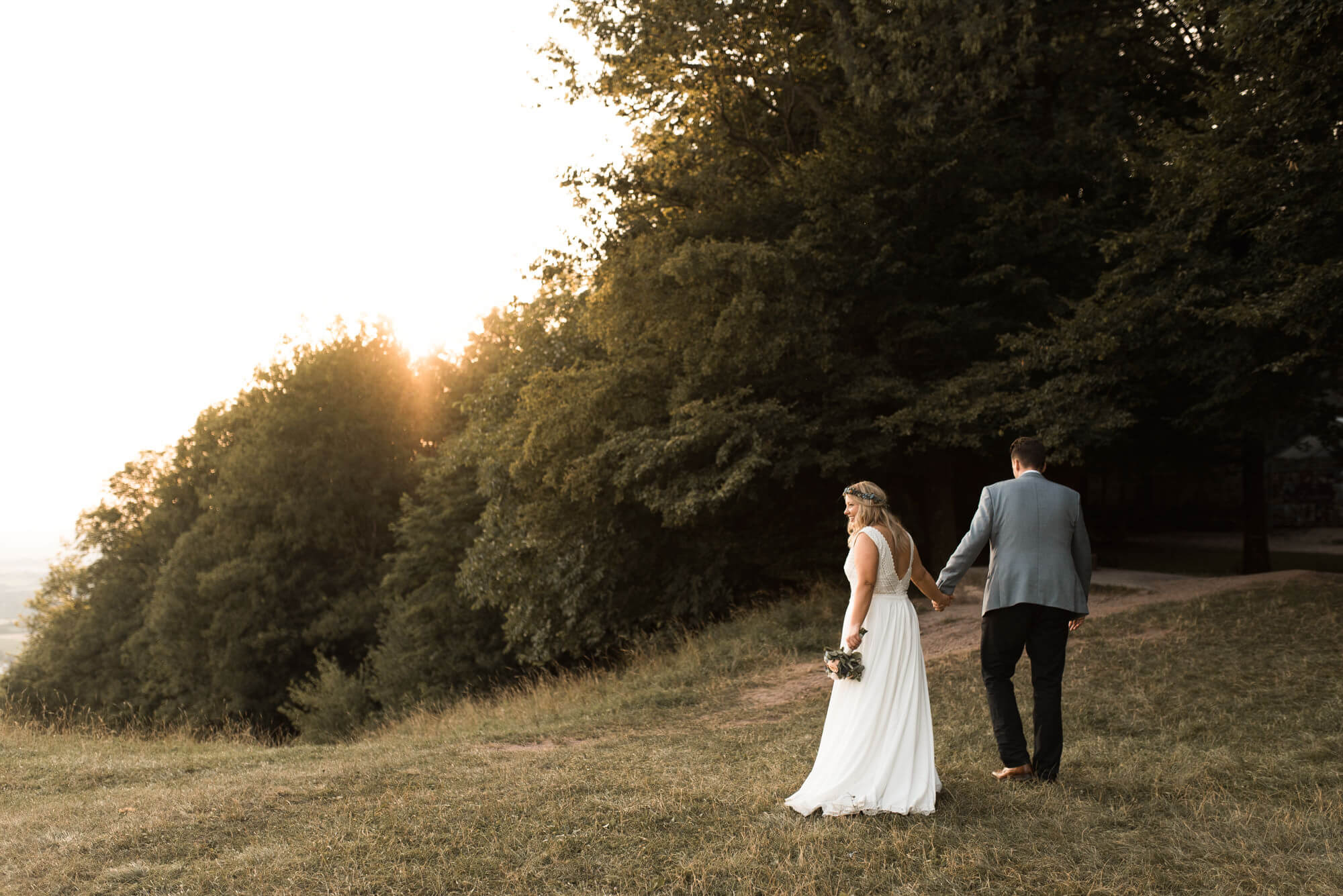 Brautpaar läuft gemeinsam in den Wald beim Sonnenuntergang auf dem Einkorn bei Hochzeit