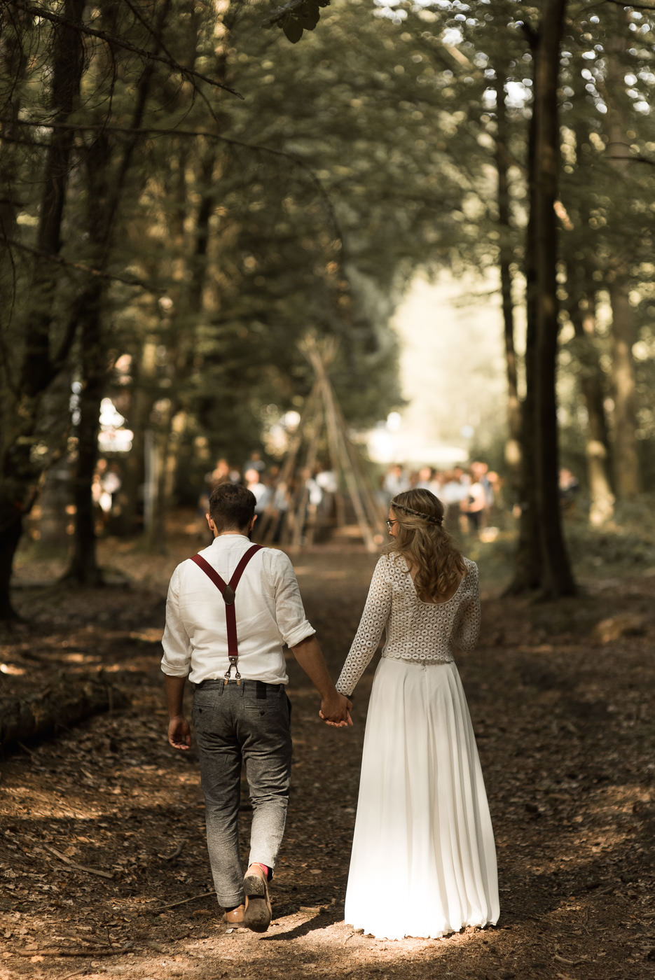 Brautpaar läuft gemeinsam Weg entlang zur Trauung im Wald