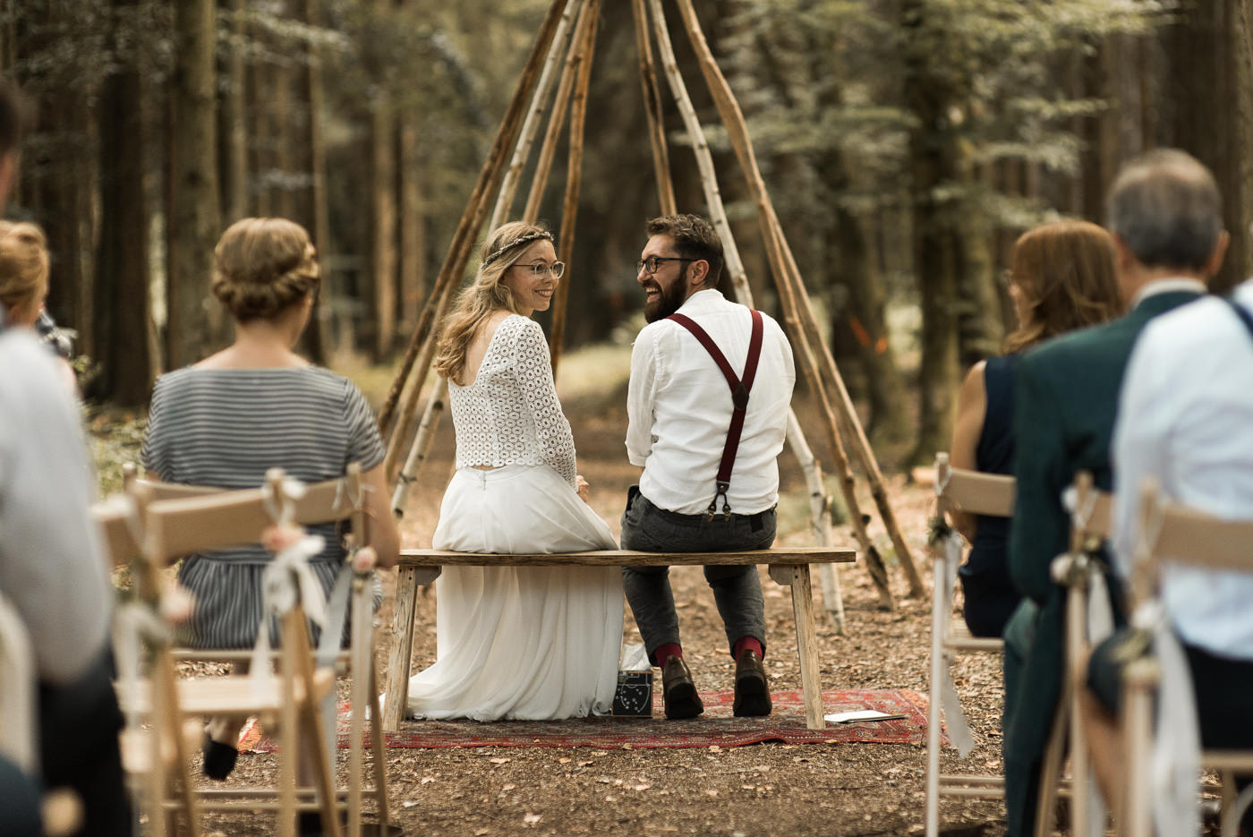 Wedding couple is laughing at their wedding guests during their forest wedding in nature