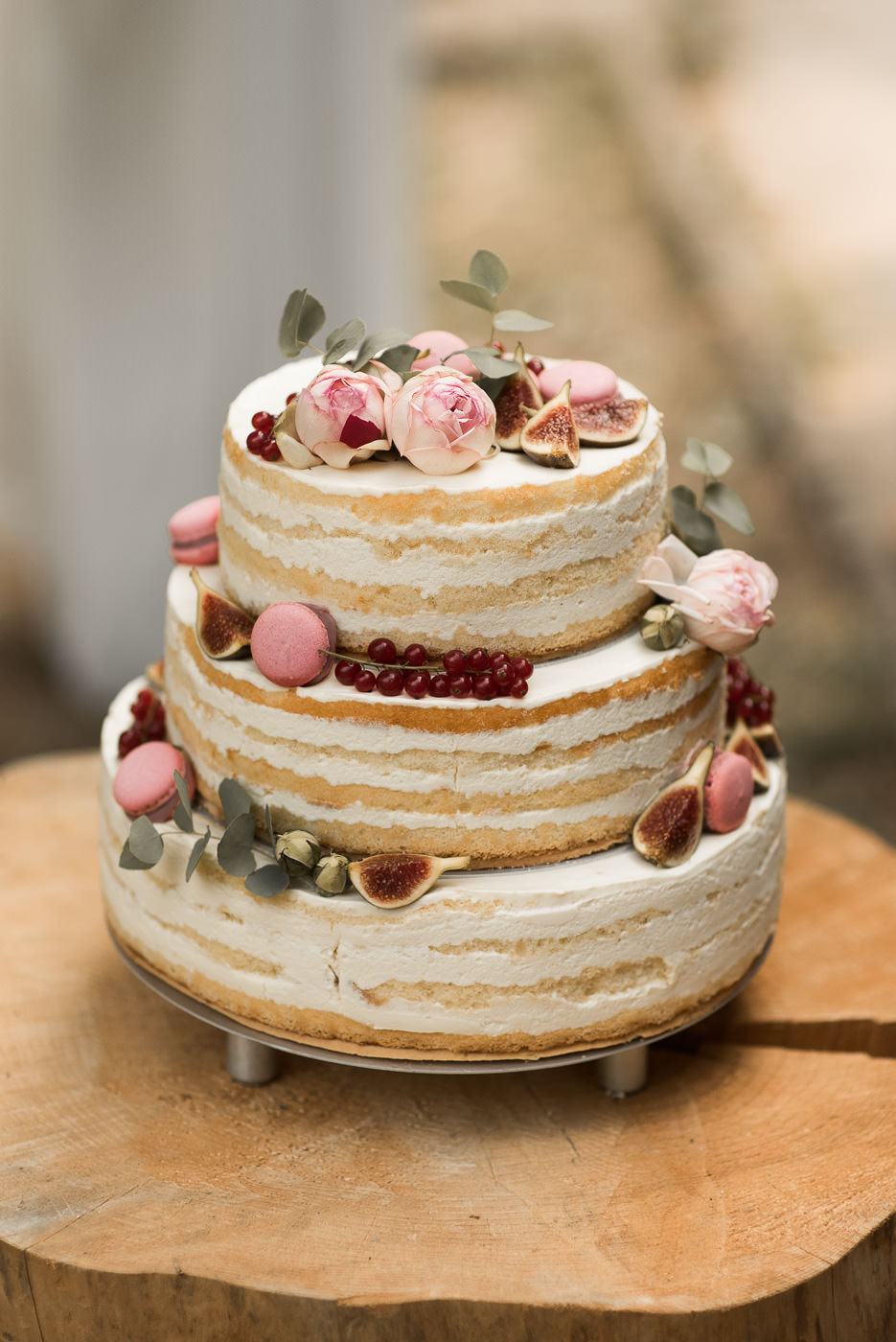 Hochzeitstorte Naked Cake mit Macarons und Johannisbeere und Eukalyptus und Feige von Cafe Ableitner in Schwäbisch Hall auf Holz