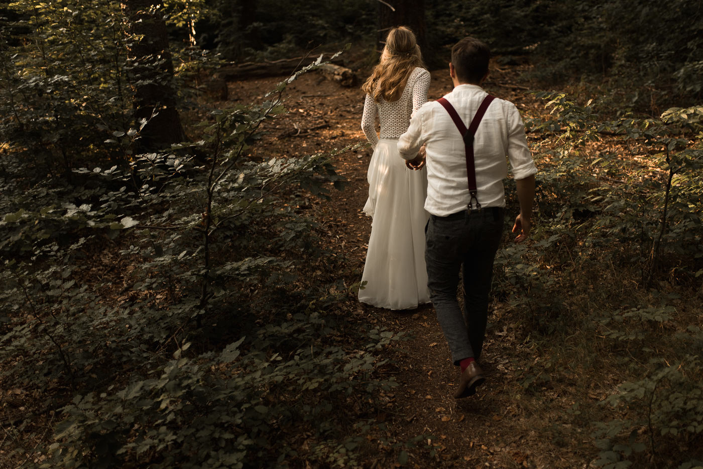 Braut entführt Bräutigam zu Wanderung durch den Wald bei Hochzeit in der Natur