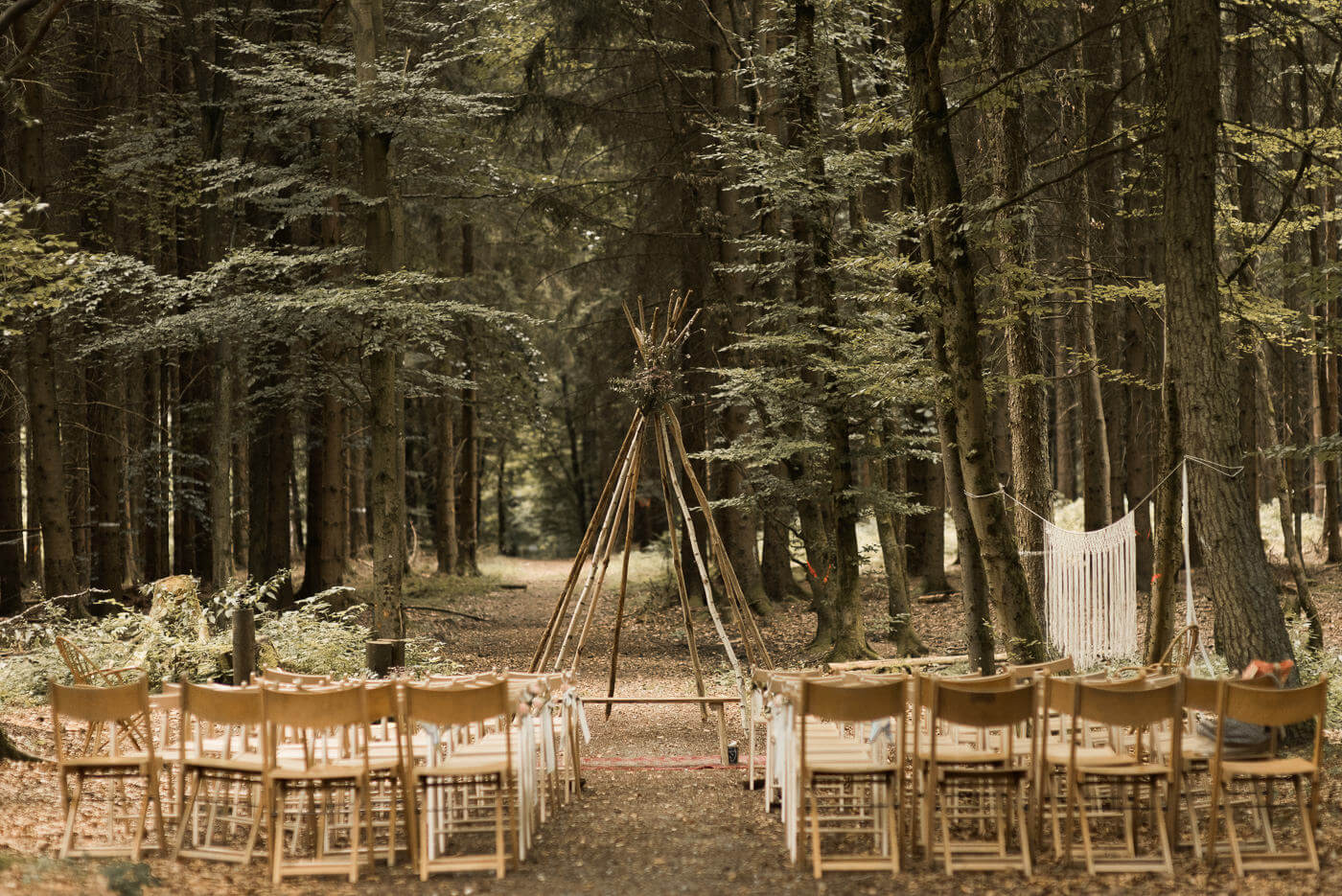 Trauung Location in Wald Hochzeit mit Tipi und Holz Klappstuehlen in der Natur