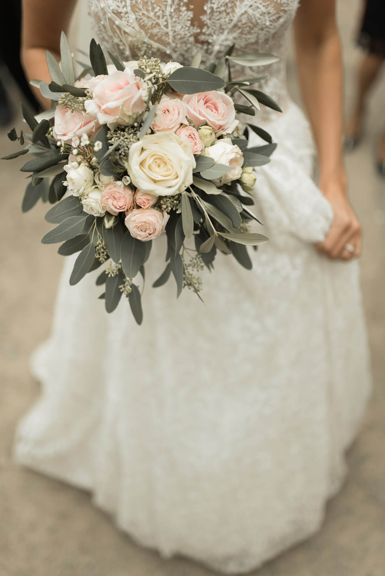 Braut zeigt Brautstrauß von Grüner Garten Mosbach mit Hochzeitskleid von Lorenzo Rossi auf Hochzeit im Landgut Lingental