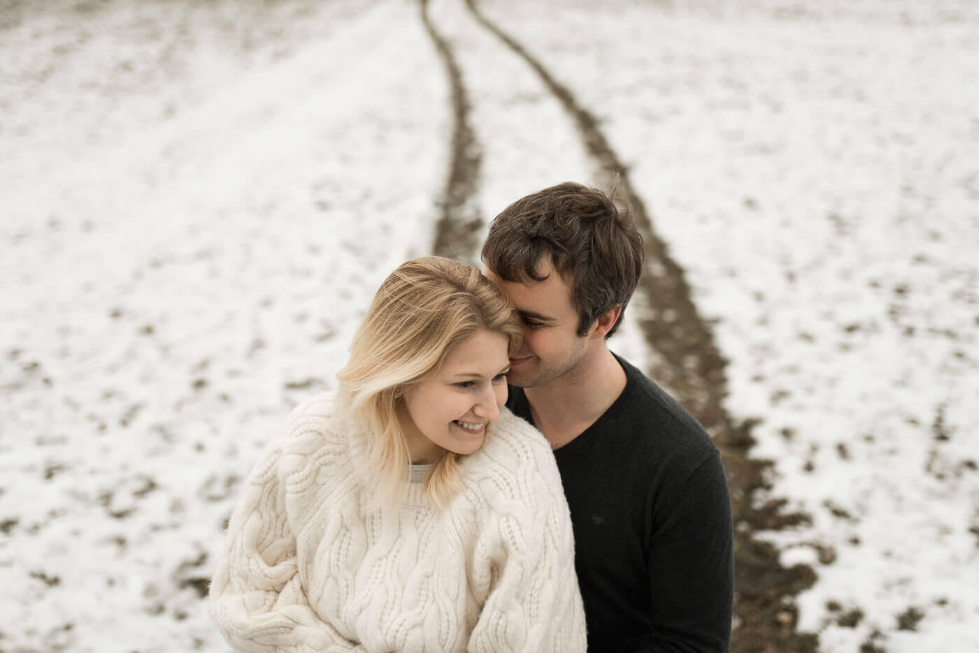 Wintershooting mit verlobtem Paar auf Schnee und sie lacht