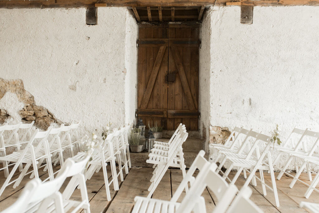 Weiße Stühle in der Festscheune von Hofgut Dornsberg bei Hochzeit
