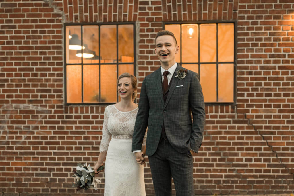 Brautpaar lacht vor alte Reederei in Heilbronn mit Backstein im Hintergrund mit alter Industriehalle als Hochzeitslocation