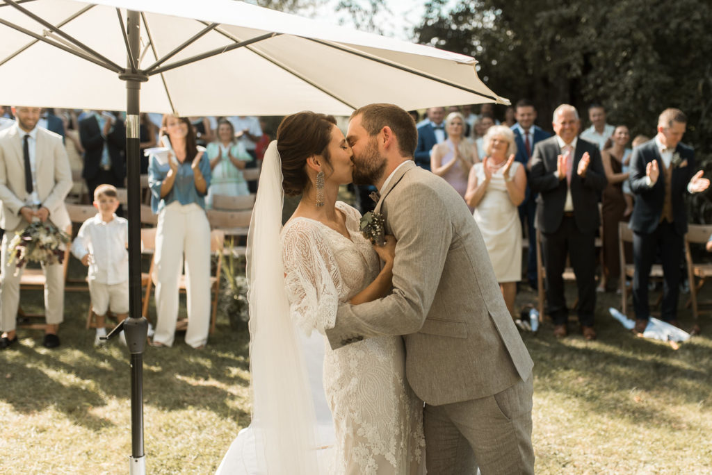 Brautpaar küsst sich bei Hochzeitsfotos und freier Trauung auf Wiese bei Landgut Halsberg am See