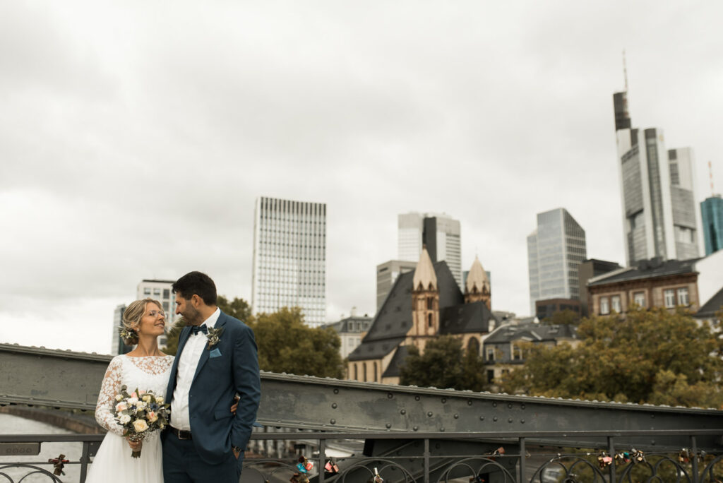 Brautpaar mit Hochzeitsfotograf in Frankfurt auf Eiserner Brücke mit Blick auf Mainhattan