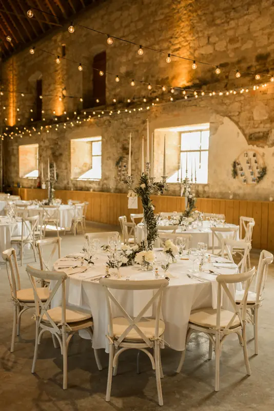 Weiße Tischdeko mit Olivenzweig und Lichterkette und Rucola als Gastgeschenk in rustikaler Hochzeitslocation mit Scheunencharakter in Ellwangen